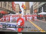 A marching band with red and white colors representing Macy. Behind it, the Macy's elves are there.